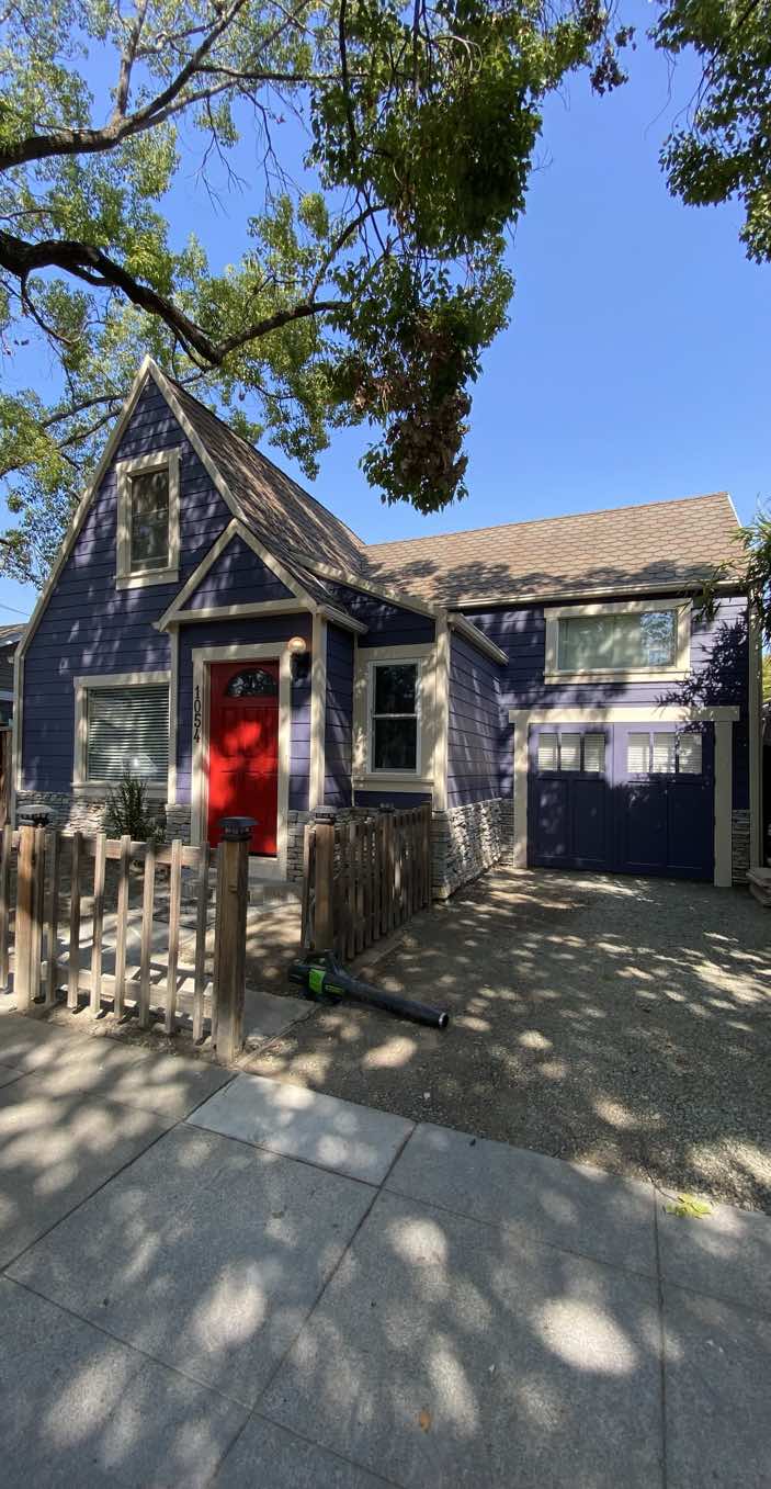 Craftsman home with deep navy siding, crisp white trim, and a bright red front door after an exterior repaint